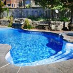 Residential inground swimming pool in backyard with waterfall and hot tub