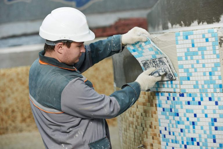 industrial tiler builder worker installing floor tile at repair renovation work