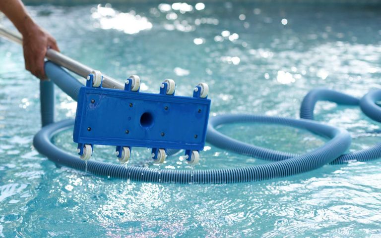 Man holding an equipment for cleaning the ground of the swimming pool